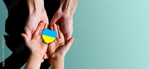 Family hands holding a heart in ucrainian colours. Peace and no war concept.