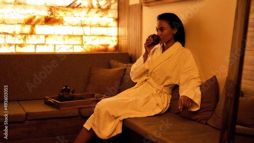Black girl drink tea from cup and thinking in spa