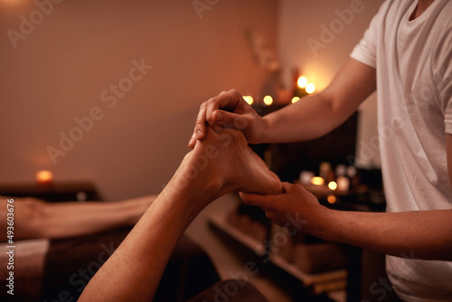 Partial of masseur doing foot massage of man