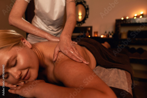 Masseur doing back massage of woman in spa salon