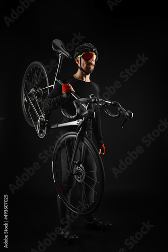 male cyclist with road bicycle on black background photo