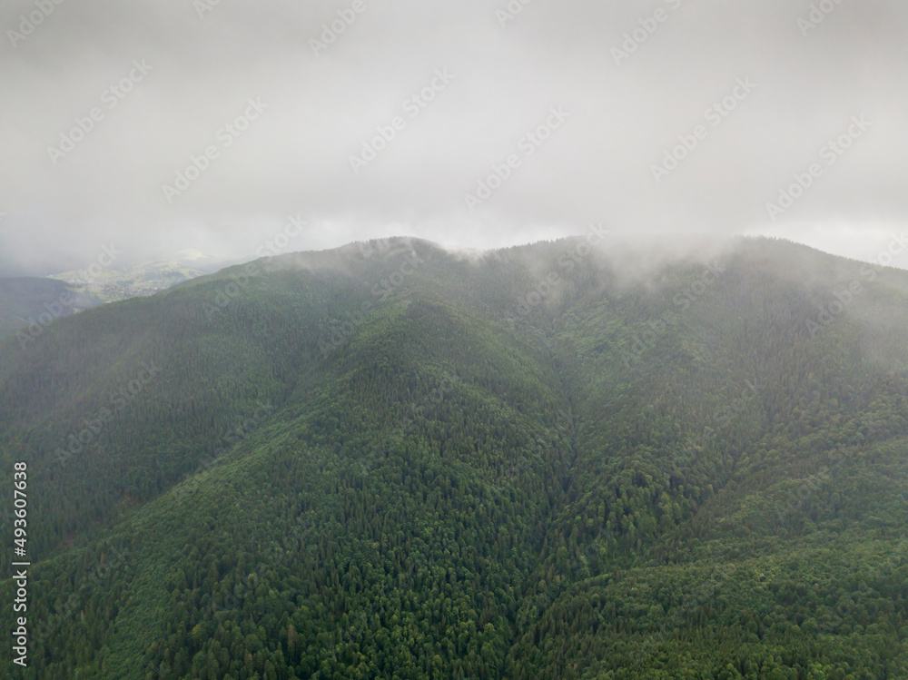 The green mountains of the Ukrainian Carpathians rest against the clouds. Aerial drone view.