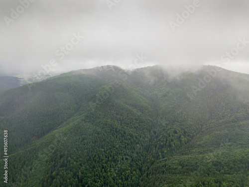 The green mountains of the Ukrainian Carpathians rest against the clouds. Aerial drone view.