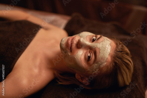 Girl with clay mask on face in spa salon
