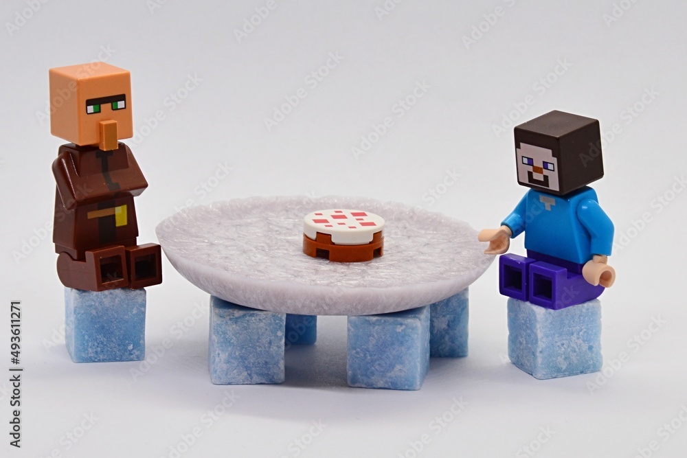 LEGO Minecraft figures of Steve and Villager sitting behind large round  table made of scented wax plate and cubes, LEGO cake is on the table. Light  grey background. Stock Photo | Adobe