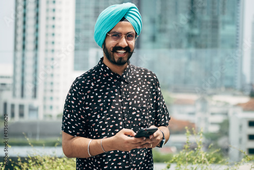 Fotografie Portrait of Happy Indian Businessman Using Mobile Phone Outdoors