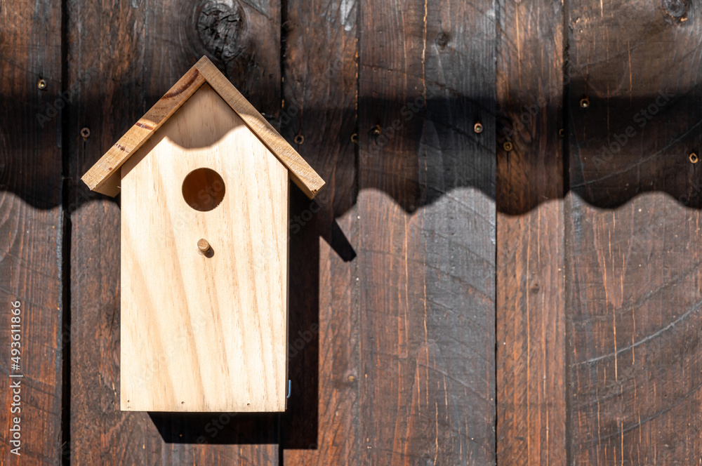 Holzwand aus braunen Brettern mit kleinem Vogelhäuschen