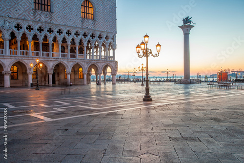 The lights of the famous Palace still on in a colorful sunrise in the idyllic St. Mark's square in Venice, Italy. © lensofcolors