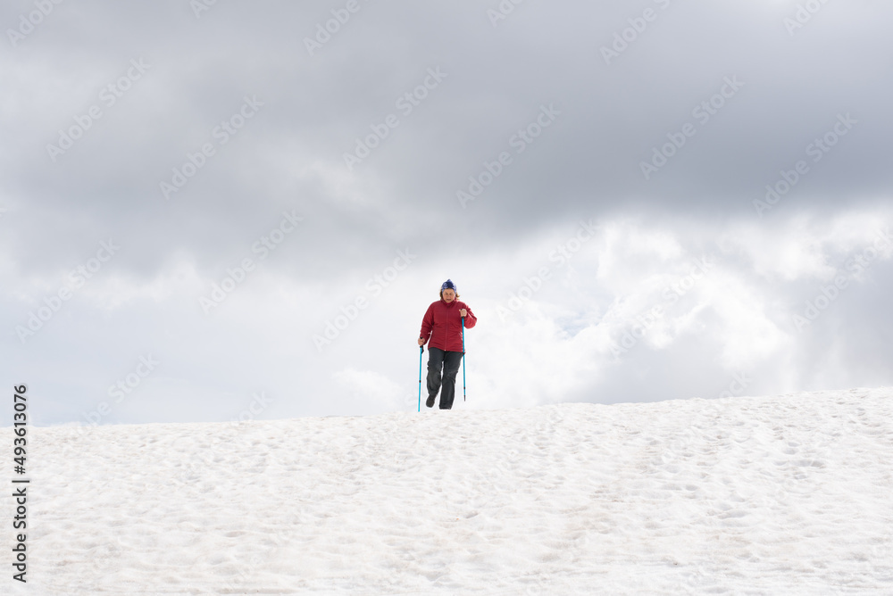 Adult woman dressed in clothes for the cold, walking along a snowy path in the French Pyrenees.