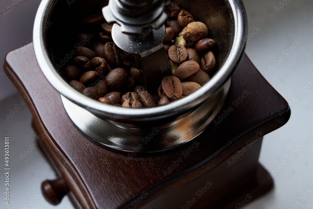 old wooden grinder and black coffee beans in daylight