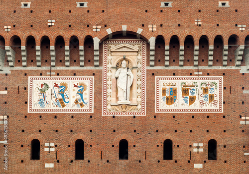 Fragment of facade of castle with statue of St. Ambrose and coats of arms of Sforza family in Milan, Italy photo