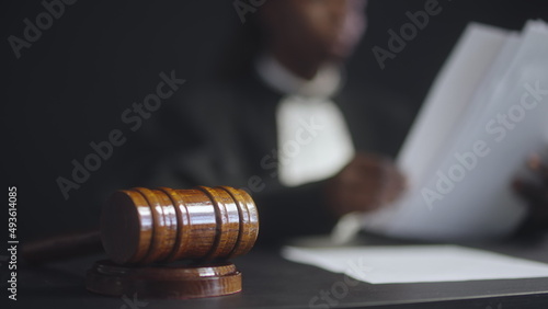 Fotografie, Obraz Female judge working with papers in court room, gavel on table, justice symbol
