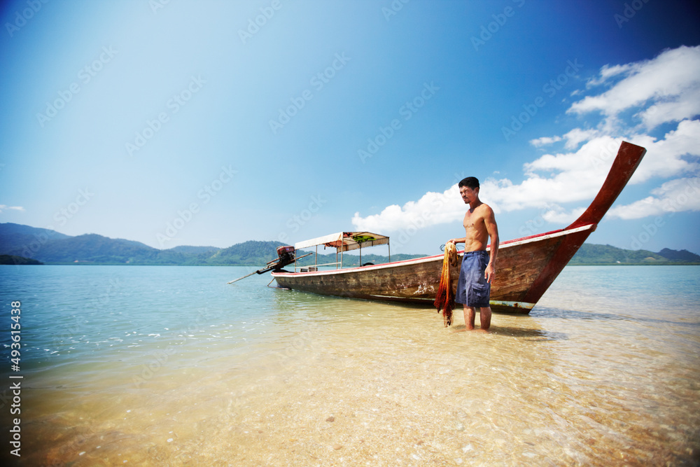 Ready to get to work. Traditional Thai long tail boat on the beach - Thailand.