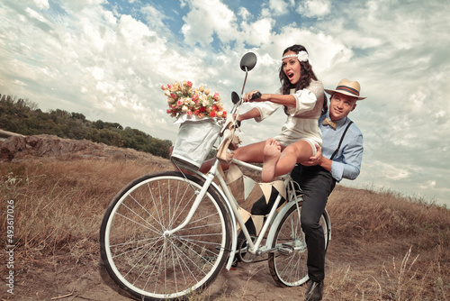 Groom and bride on a bicycle with just married sign and cans attached