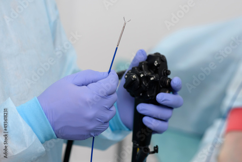 Instruments for gastroscopy close-up. The doctor holds in his hands a flexible endoscope and forceps to remove foreign bodies from the esophageal cavity. Endoscopy and minimally invasive surgery. photo