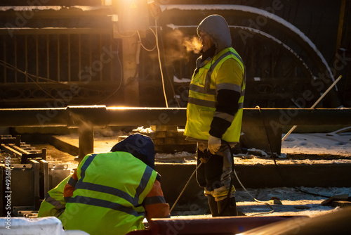 Employees of the road service in special yellow vests perform work on the repair of the roadway. Restoration of the deformation seam of the automobile bridge.