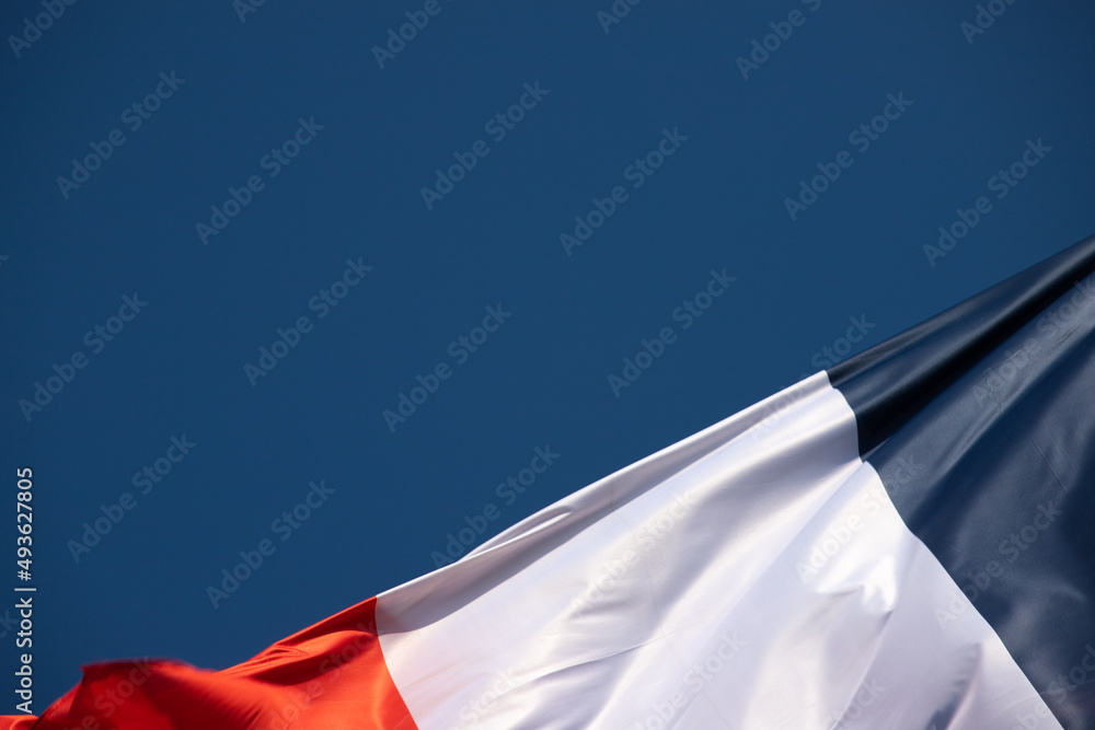 drapeau français tricolore bleu, blanc, rouge qui bouge dans le vent avec  en arrière plan un beau ciel bleu. Emplacement libre pour le texte. Photos  | Adobe Stock