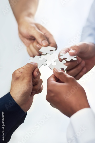 Theyre not puzzled by success. High angle shot of a group of unidentifiable businesspeople holding puzzle pieces together.
