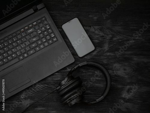 Foto Gray laptop and headphones with a microphone on a black wooden surface
