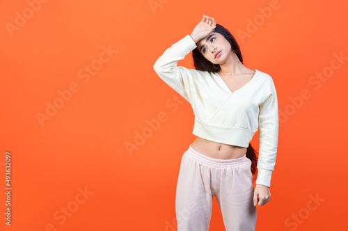 Despair and Hopelessness concept with tired woman holding her hand to her face. Orange wall background with copy space. photo