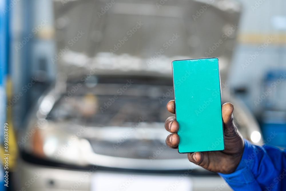 close shot of car machanic hands using green screen mobile phone with uniform in front of car - concept of online booking service, advertisement and application promotion. close shot of car machanic hands using green screen mobile phone with uniform in front of car - concept of online booking service, advertisement and application promotion.