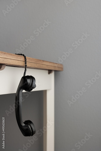 Alter Telefonhörer hängt an der Schnur von Tischkante