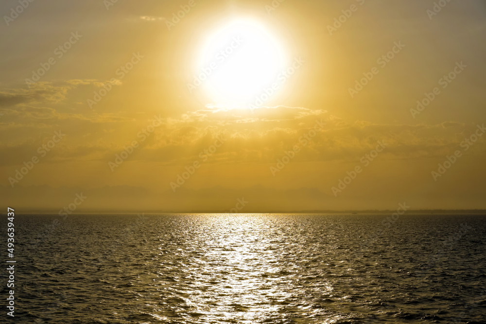 Golden sunset sun over sea. Sun's rays break through clouds. Magnificent seascape. Copy space.