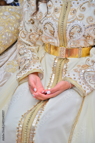 Details of a White Moroccan caftan for women, with her ​​embroidery and golden lace.