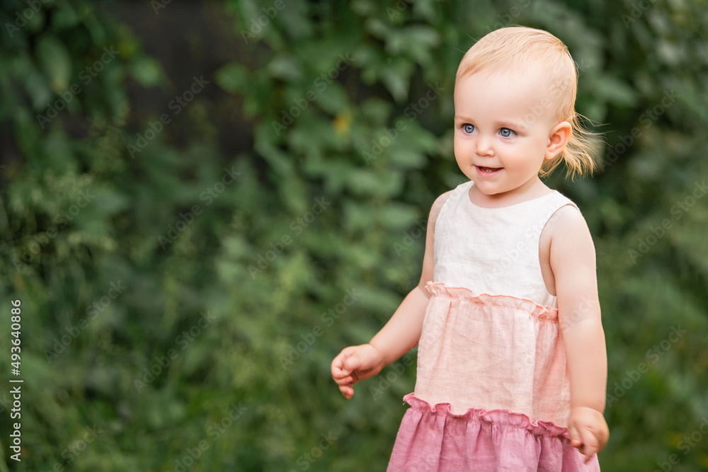 Little blue-eyed girl walks in a garden in summer in long vintage linen dress Little blue-eyed girl walks in a garden in summer in long vintage linen dress