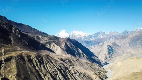A panoramic view on dry Himalayan landscape. Located in Mustang region  Annapurna Circuit Trek in Nepal. In the back there is snow capped Dhaulagiri I. Barren and steep slopes. Harsh condition.