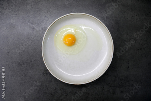 Raw egg in a plate on the kitchen table