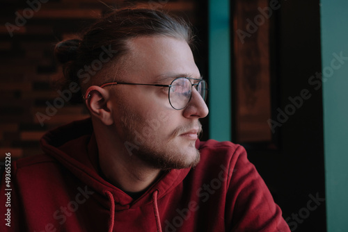 Portrait of happy male freelancer in optical eyewear for vision correction smiling at camera during break from web working online, cheerful hipster blogger sitting in cafe with mockup laptop