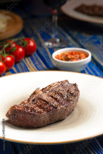 Roasted steak ,cherry tomatoes, salt and pepper on blue wooden table.