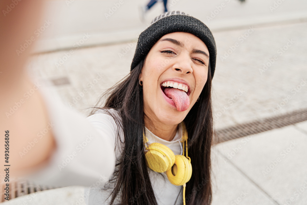 Latina Taking A Selfie With Her Smart Phone Sticking Out Her Tongue And Winking Hispanic Woman 