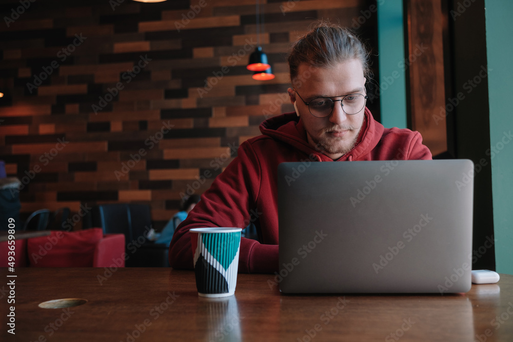 Portrait of happy male freelancer in optical eyewear for vision correction smiling at camera during break from web working online, cheerful hipster blogger sitting in cafe with mockup laptop Portrait of happy male freelancer in optical eyewear for vision correction smiling at camera during break from web working online, cheerful hipster blogger sitting in cafe with mockup laptop
