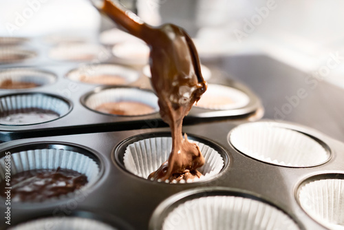 Muffins backen - Teig wird mit Löffel in Muffinform gegeben und für das Backen im Ofen vorbereitet photo