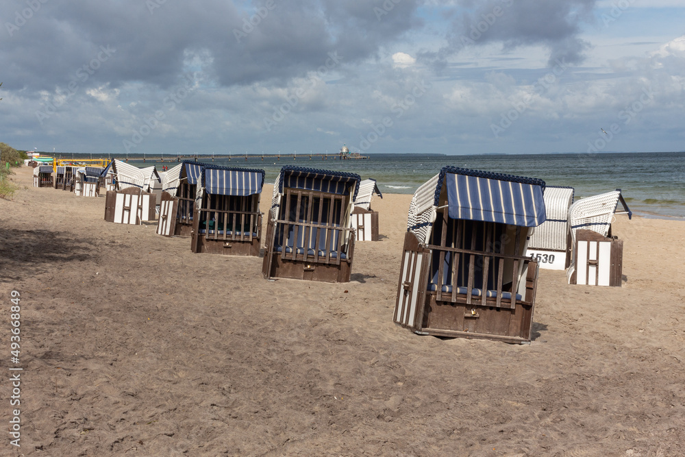 Lonely beach wooden wicker chairs on beach cloud sky Baltic Sea, Germany