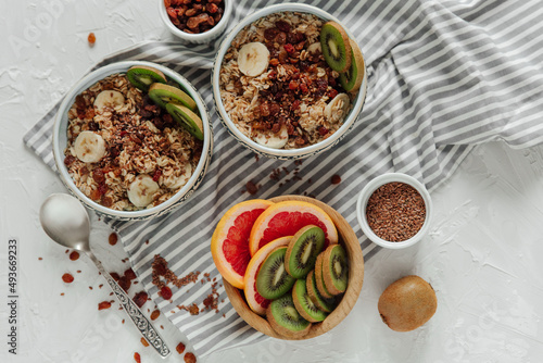 Oatmeal porridge bowl with with kiwi, banana, raisins in blue bowl. Healthy breakfast food, vegetarian breakfast. Top view