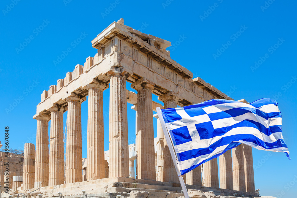 Obraz premium World famous iconic Parthenon on the Acropolis Hill in Athens, Greece with Greek flag against blue sky