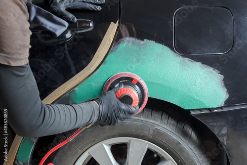 Grinding body parts with a pneumatic grinder before painting.
