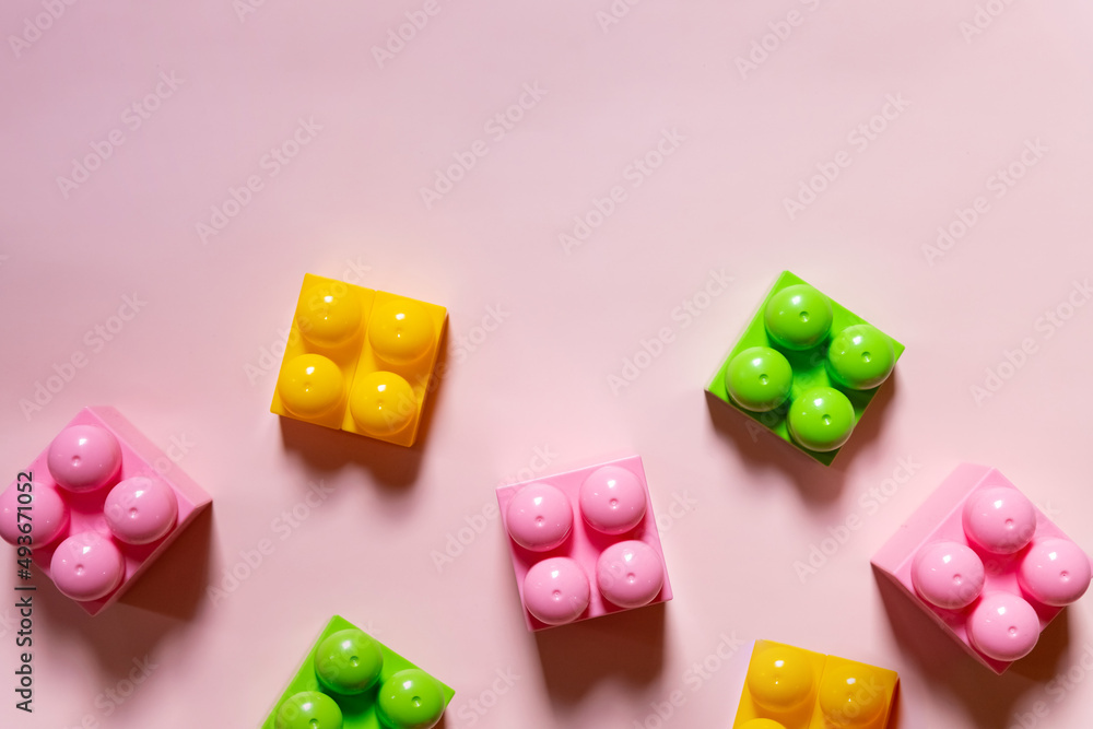 Colorful plastic building blocks flat lay. pink background. Child developing game. Pattern.children's bricks for construction. Building blocks background. Developing toys, copy space Colorful plastic building blocks flat lay. pink background. Child developing game. Pattern.children's bricks for construction. Building blocks background. Developing toys, copy space