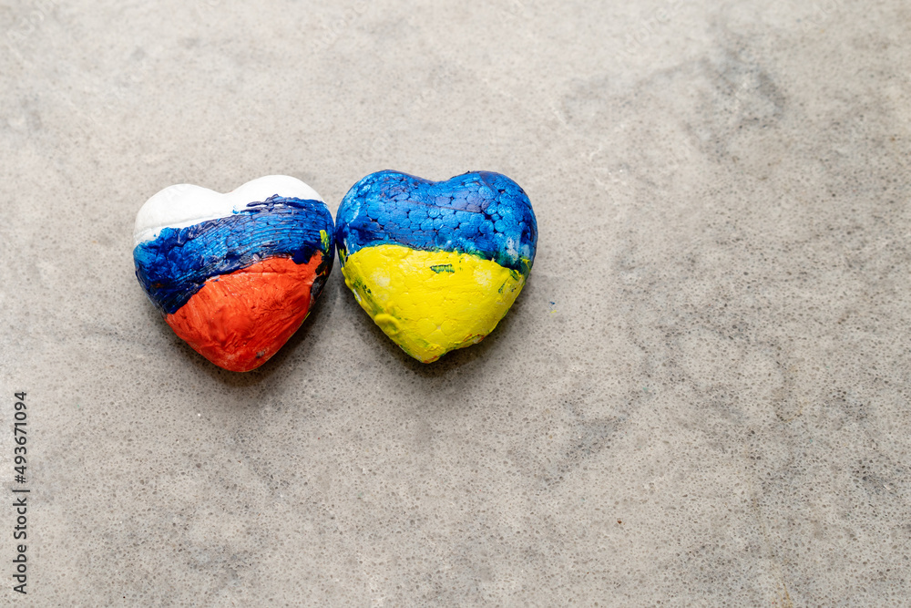 Obraz premium National flags of Ukraine and Russia of heart shape on grey marble background. Creative image about peace between Ukrainian and Russian people, talks, Negotiation.