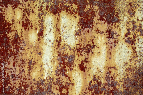 Brown abstract background with beige orange red hues. A weathered, rust-eaten textured sheet of metal with traces of paint residue.