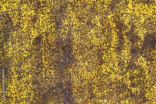 Brown abstract background with acid yellow green red hues. A rust-eaten textured sheet of metal with remnants of paint marks.