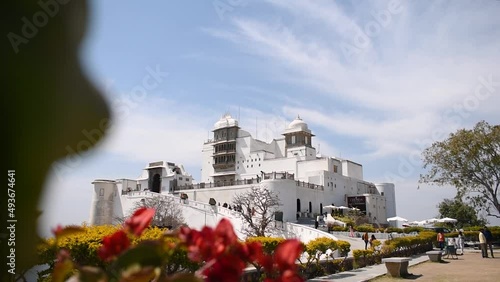 The Monsoon Palace or SajjanGarh Palace in Udaipur, Rajasthan, India. White color Indian old palace under blue sky, palace view with flowers from garden. Historic travel destination in India photo
