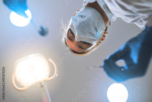 Just remain calm and Ill do the rest. Low angle shot of a focused young female dentist wearing a surgical mask while attempting to work on a patients teeth.