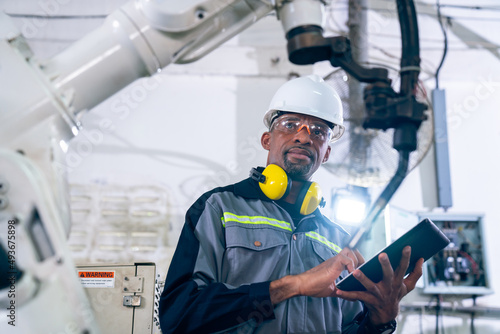 African American factory worker working with adept robotic arm in a workshop . Industry robot programming software for automated manufacturing technology . photo