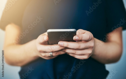 Downloading a new app. Studio shot of an unrecognizable young woman using her cellphone against a grey background.