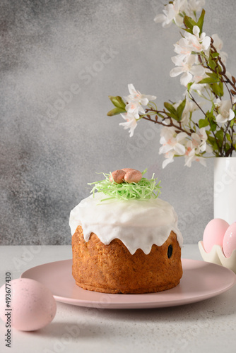 Easter cake, pink pastel eggs and spring blossom flowers on gray background. Vertical format. Holidays traditional food. Christian custom.