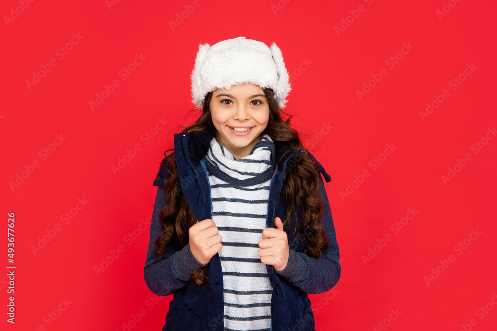 smiling teen girl on red background. portrait of child wearing warm clothes.